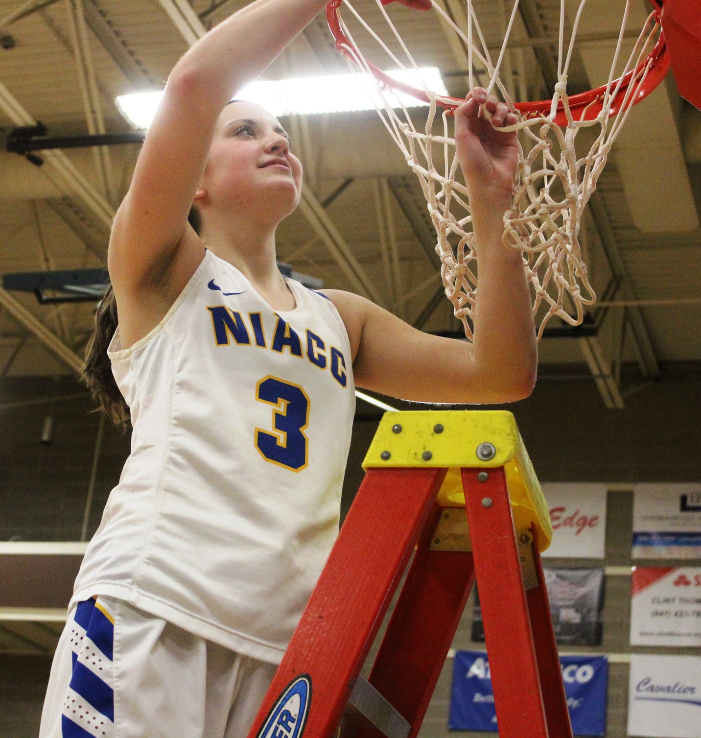 NIACC's Mandy Willems takes her turn cutting down the net after winning the regional title on Sunday in the NIACC gym.