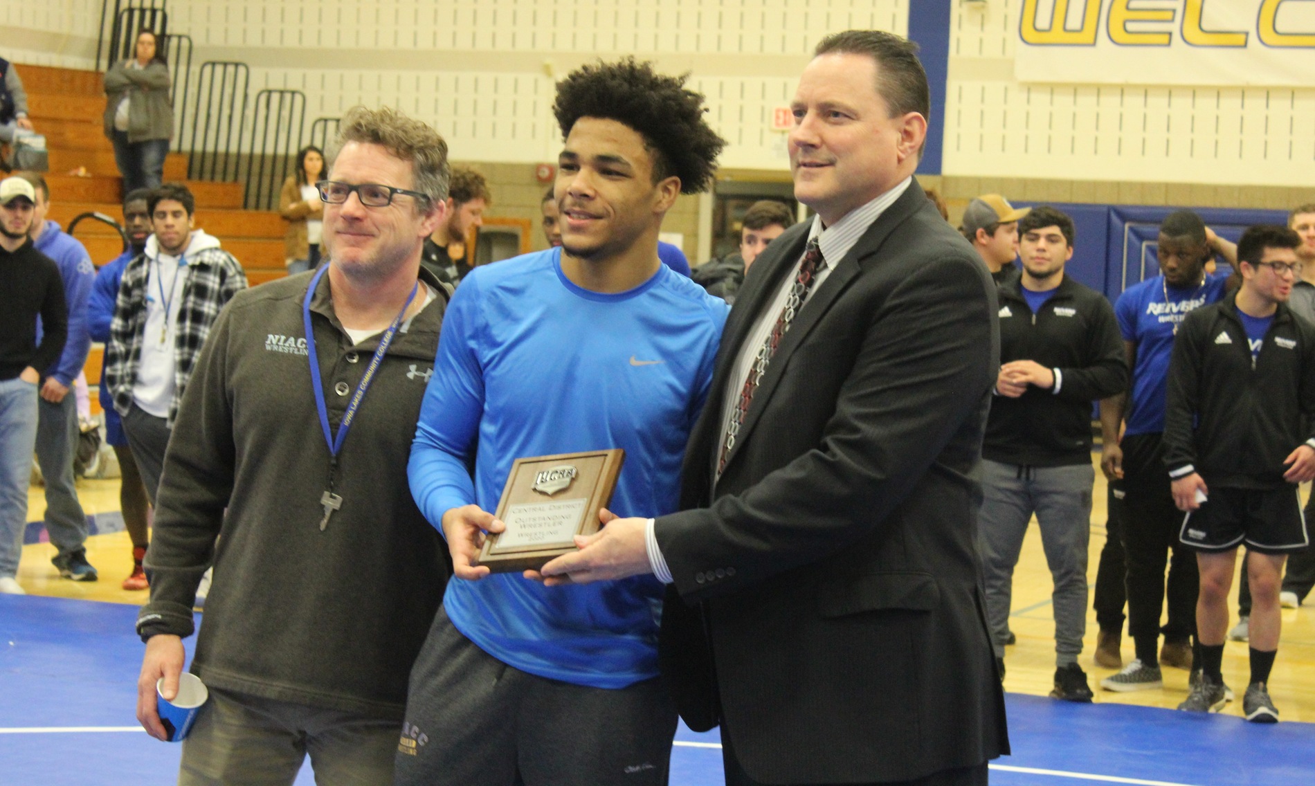 NIACC's Christian Minto receives the district tournament's most outstanding wrestler award with coach Steve Kelly (left) and ICCAC commissioner Thom McDonald.